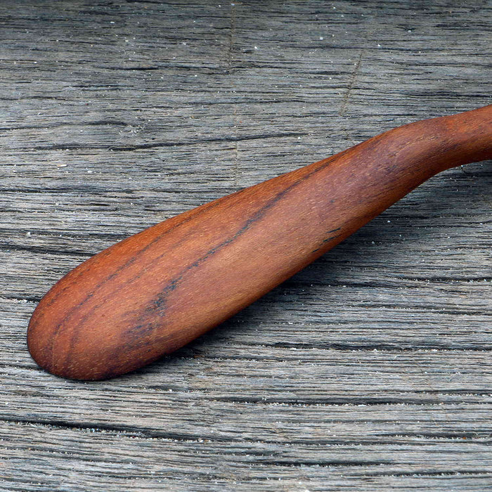 Close up of wooden butter spreader displayed on a wooden surface