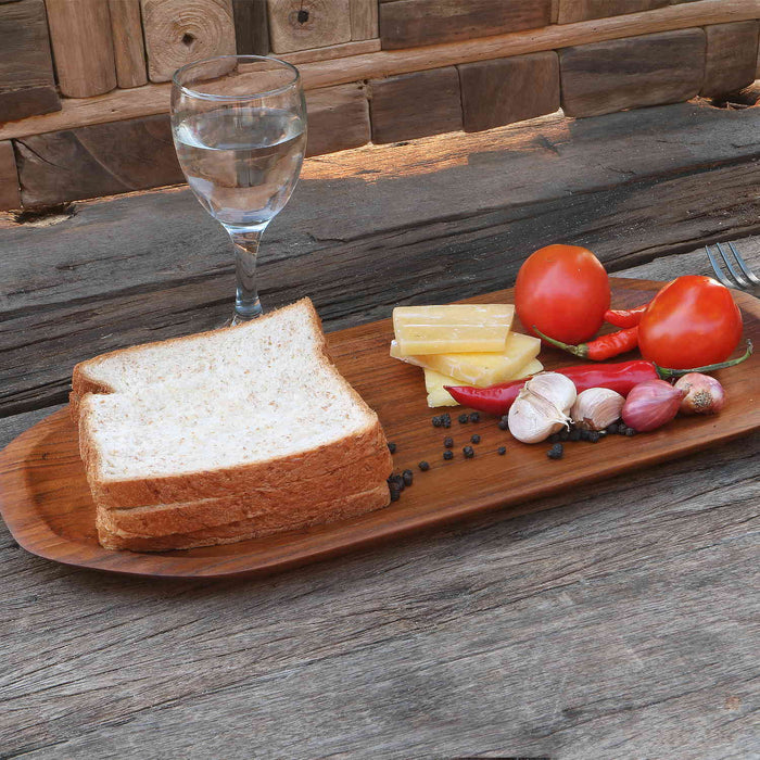 Large teak plate filled with assortment of food on top next to a glass of water displayed on a wooden surface