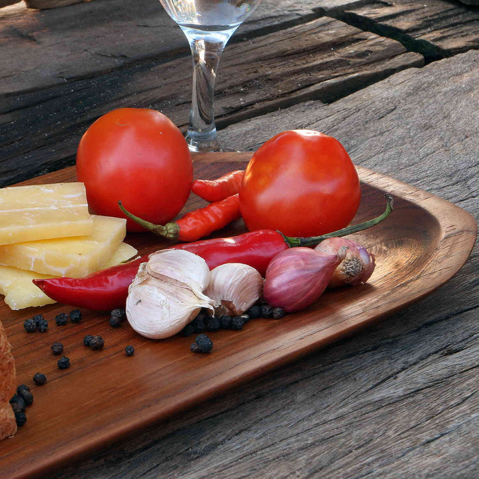 Close up of one side of large teak plate filled with assortment of food on a wooden surface