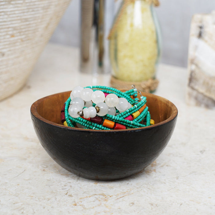 Rico & Plato chico teak bowl with black exterior with jewelry inside displayed on a granite countertop