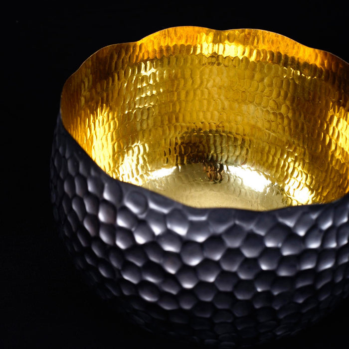 Close up of copper bowl with black accent displayed on a black background