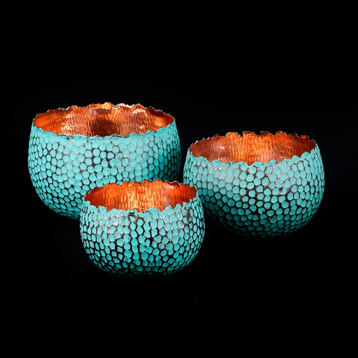 Three turquoise textured bowls with copper rims on a black background