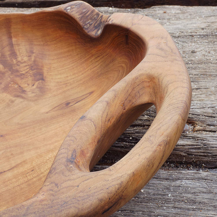 Close up of handles of Rico & Plato dora teak serving bowl with integral handles displayed on a wooden surface