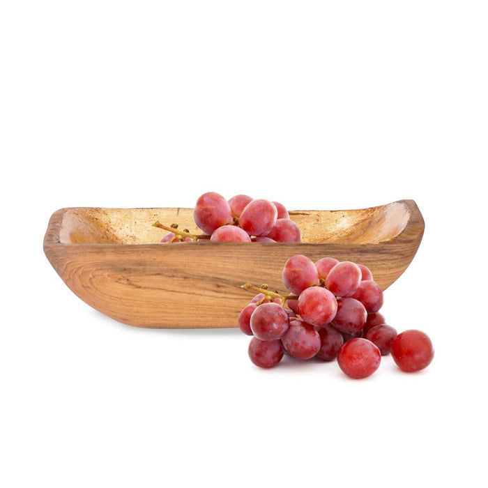 Small teak bowl with gold leaf interior filled with grapes and grapes on the side displayed on a white background