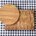 Rectangular end grain cutting board and a round plate on a black and white checkered background
