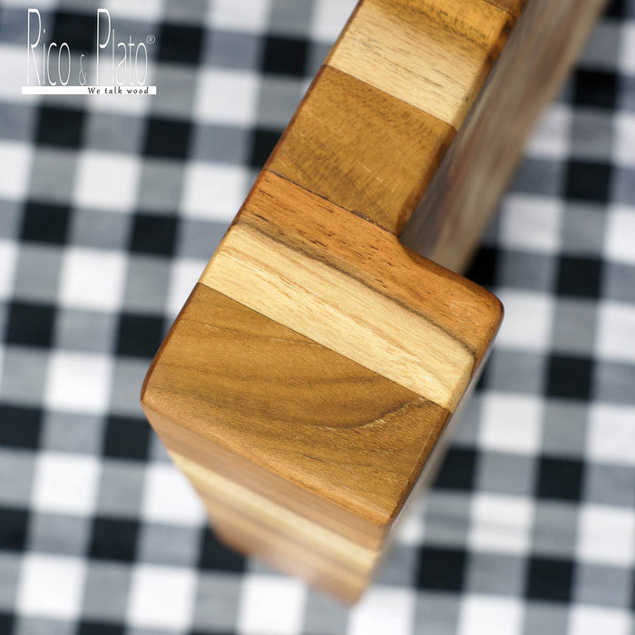 Edge of an end grain cutting board with a lift edge on a black and white checkered background
