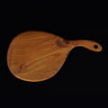 Top view of teak cutting board/serving platter with curved handle displayed on a black background
