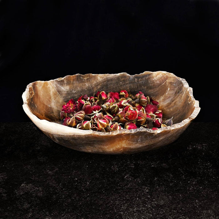 Onyx bowl filled with dried up flower buds displayed on a black surface