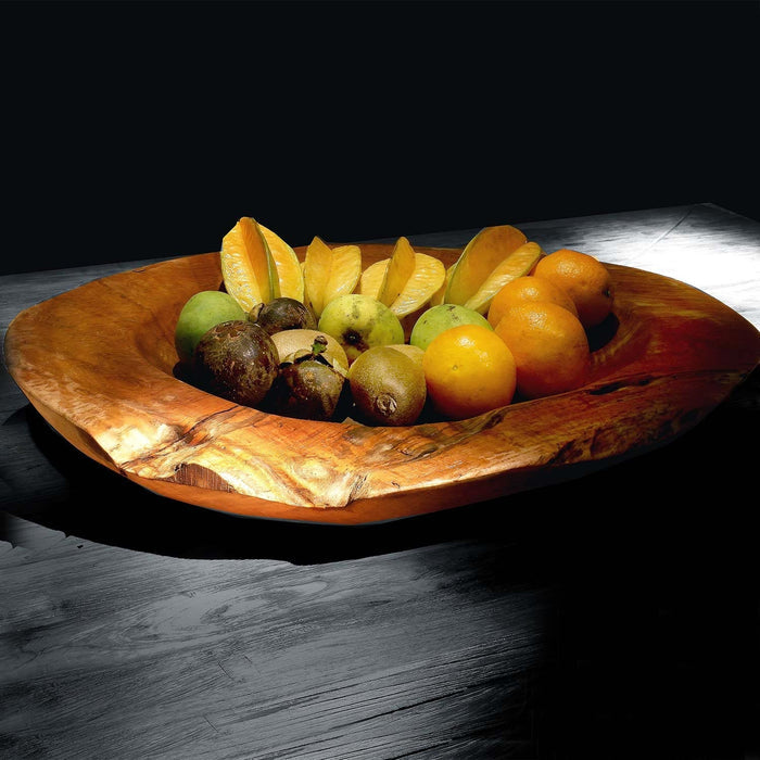 Small teak bowl filled with an assortment fruits displayed on a black wooden surface