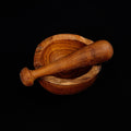 Teak pestle on top of mortar displayed on a black background