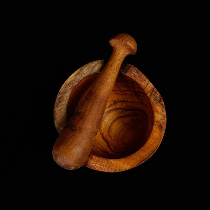 Top view of teak pestle on top of a mortar displayed on a black background