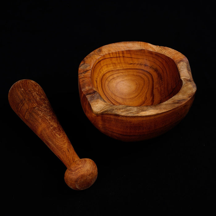 Teak pestle next to a mortar displayed on a black background