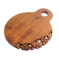 Teak cutting serving board with decoration carved on one side with a handle on the top displayed on a white background