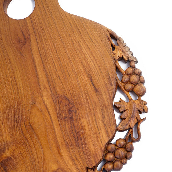Close up of decoration carved on one side of teak cutting serving board on the top displayed on a white background