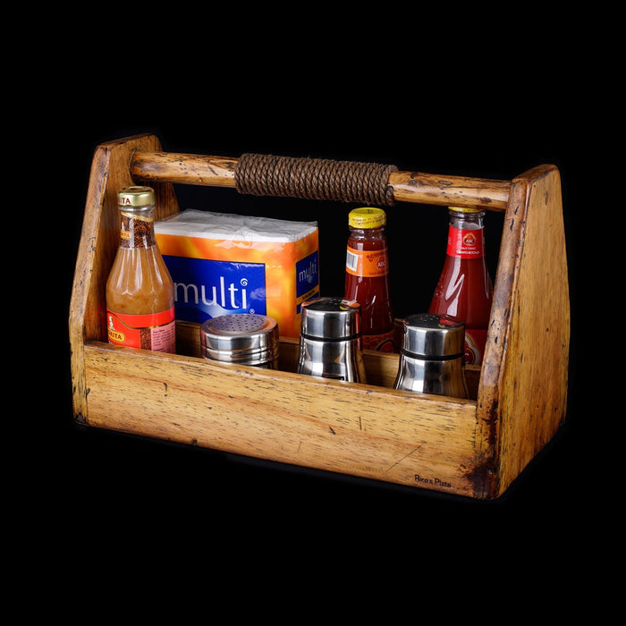 Front view of large pine wooden barbecue grill caddy with partial roped handle and an assortment of barbecue accessories inside displayed on a black background