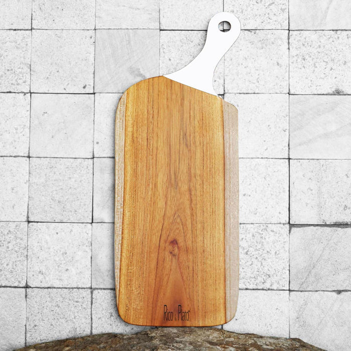 Teak cutting board with white handle and Rico & Plato displayed vertically on a tiled background