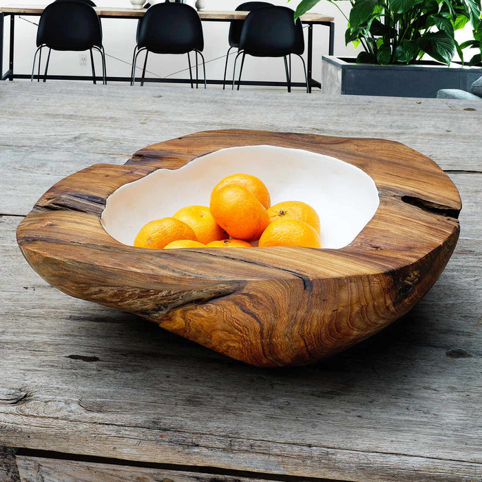 Extra large teak bowl with white interior filled with oranges displayed on a wooden surface