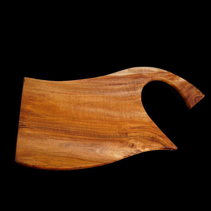 Teak cutting board with curved handle displayed horizontally on a black background