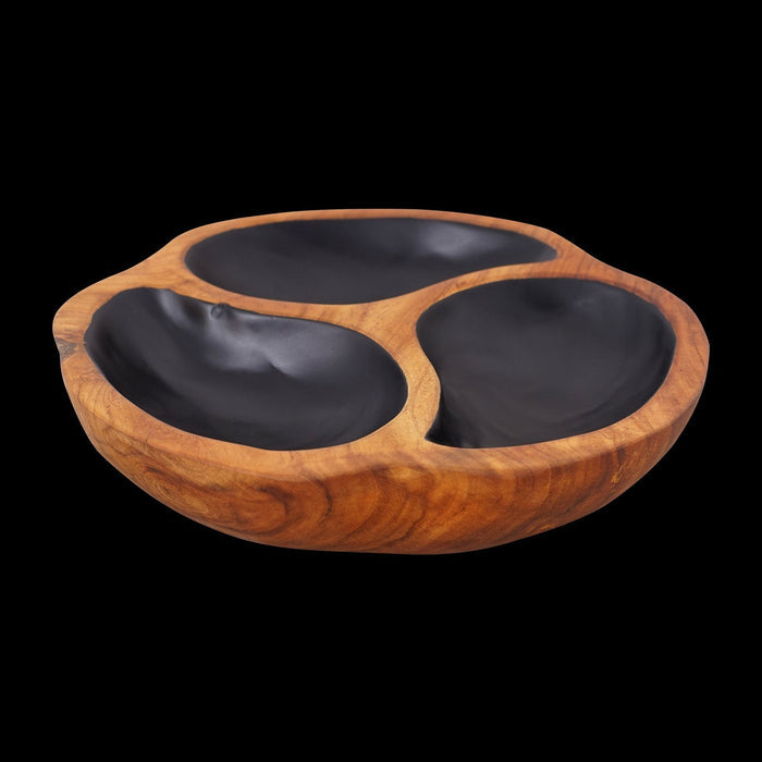 A hand-carved teak wood serving bowl with three compartments, featuring a black painted interior and placed against a black background.