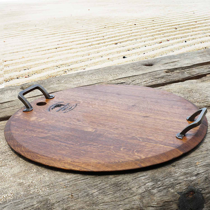 Oak serving platter with metal handles displayed outside on a wooden surface
