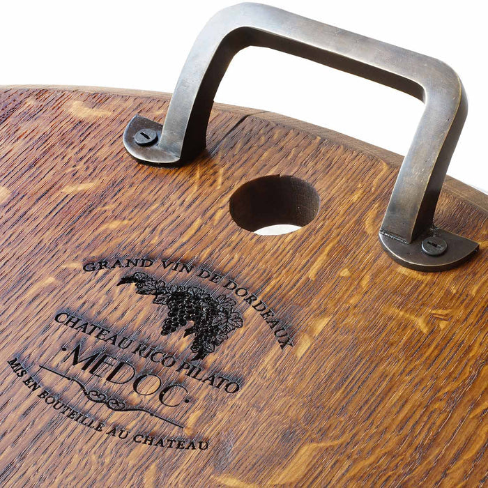 Close up of inscription and metal handle of oak serving platter displayed on a white background