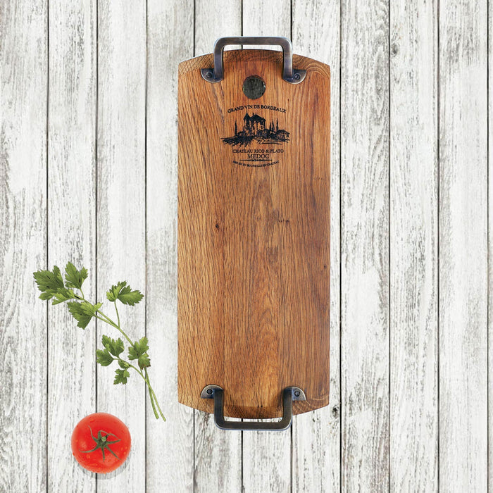 Rectangular oak serving platter with metal handles next to tomato and herbs displayed vertically on a white, wooden surface