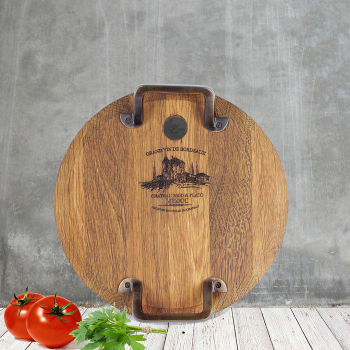Small oak serving platter with metal handles next to tomatoes and herbs displayed vertically on a wooden surface