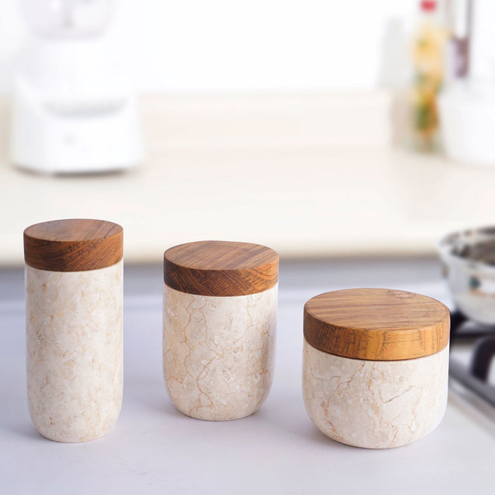 Set of 3 glossy marble pots with wooden lids of different sizes displayed in a row in a  kitchen setting