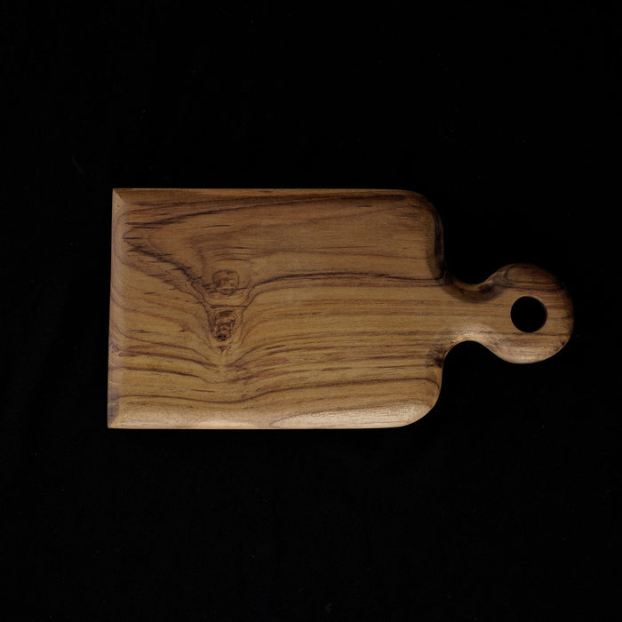 Top view of Rico & Plato onilemo teak cutting board serving platter displayed horizontally on a black background