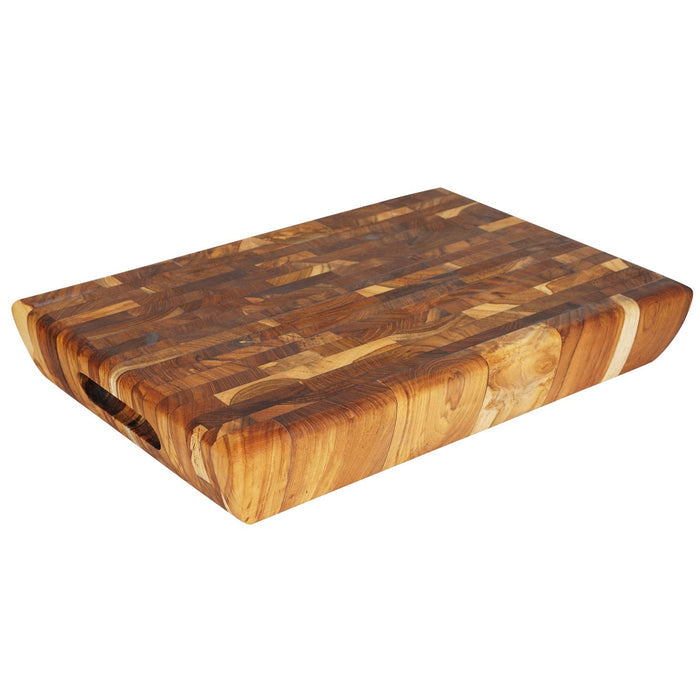 End grain teak cutting board with carved handles displayed on a white background