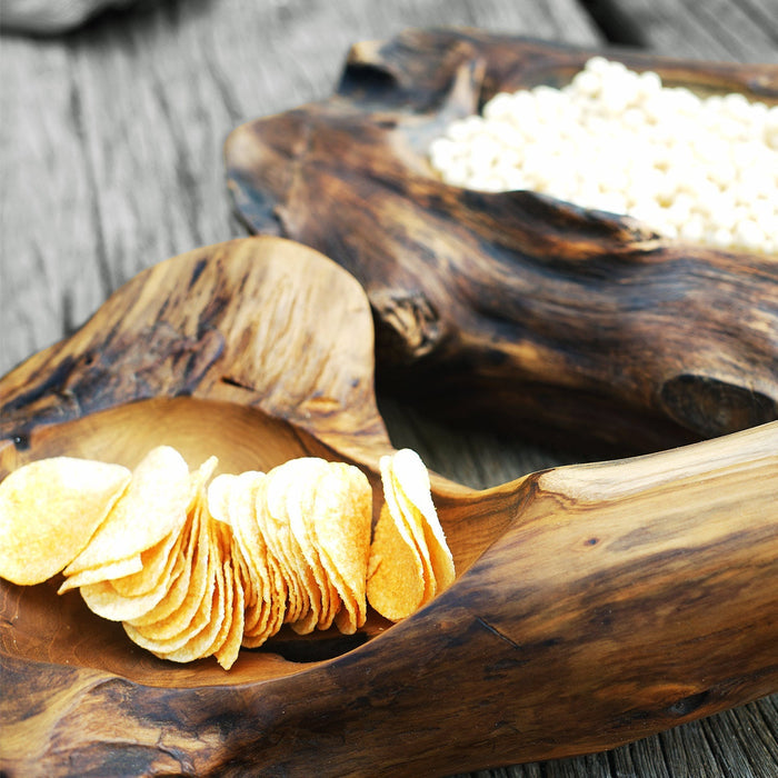Close up of two teak bowl with natural texture filled with chips and white balls displayed on a wooden surface