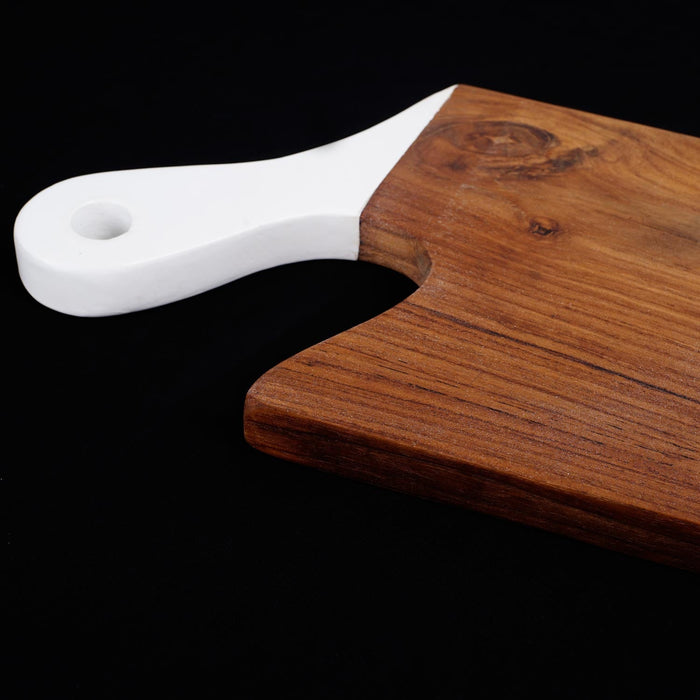 Close up of white handle of teak cutting board displayed on a black background