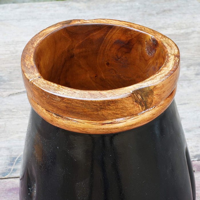 Top view of a close up of copper leaf accent rim of black teak vase displayed on a wooden background
