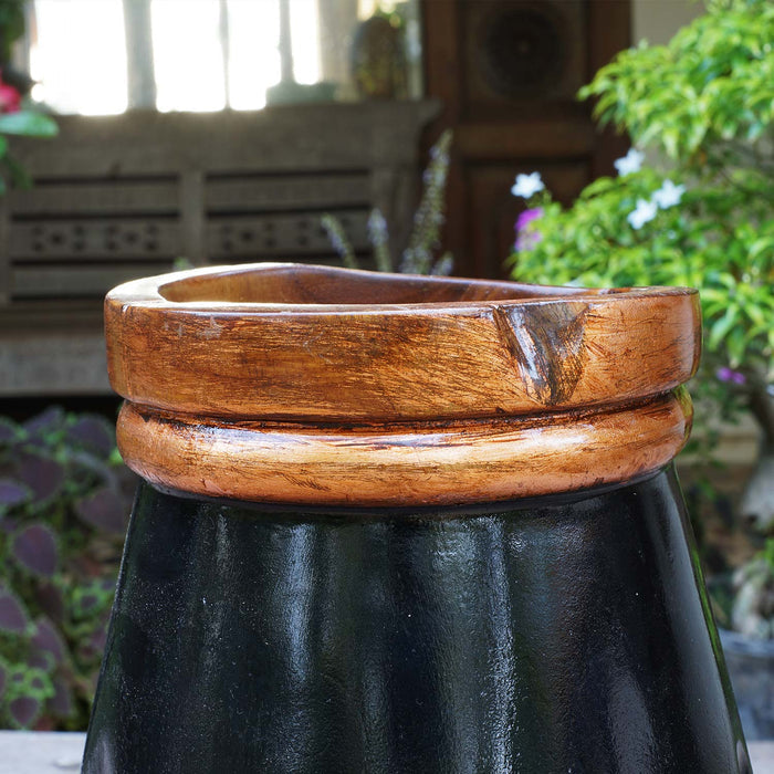 Close up of copper leaf accent rim of black teak vase in an outdoor setting