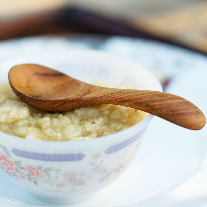 Small wooden baby spoon displayed on a bowl of oatmeal
