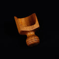 Small teak lentil scoop with a small handle displayed on a black background