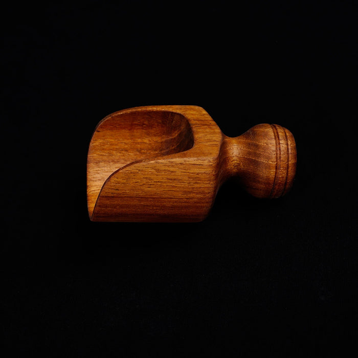 Small teak lentil scoop with small handle displayed horizontally on a black background