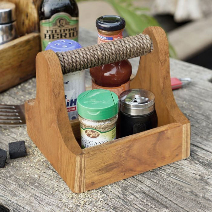 Small teak barbeque grill accessory square caddy with grilling accessories inside displayed on a wooden surface outside
