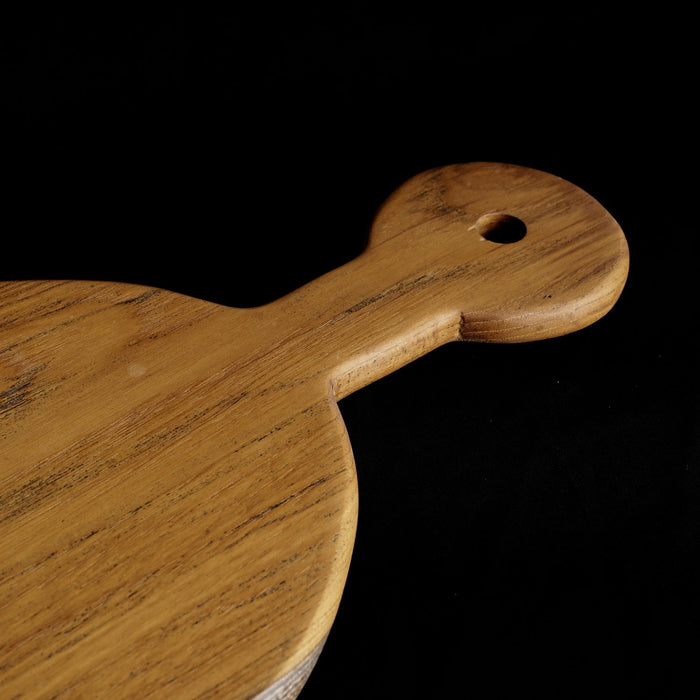 Close up of handle of Rico & Plato sorrel teak cutting board serving platter displayed on a black background