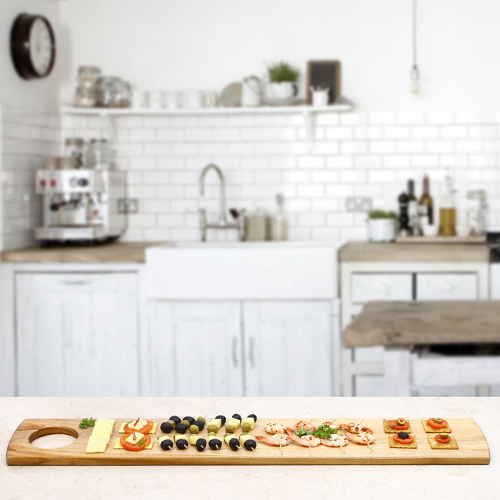 Rico & Plato teak serving board with charcuterie material on board displayed in a kitchen setting