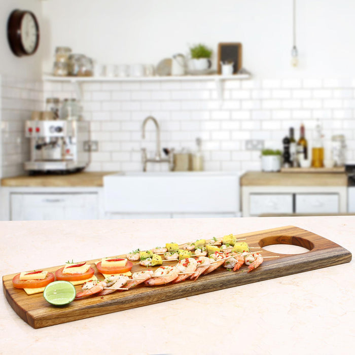 Rico & Plato teak serving board with charcuterie material on board displayed in a kitchen setting