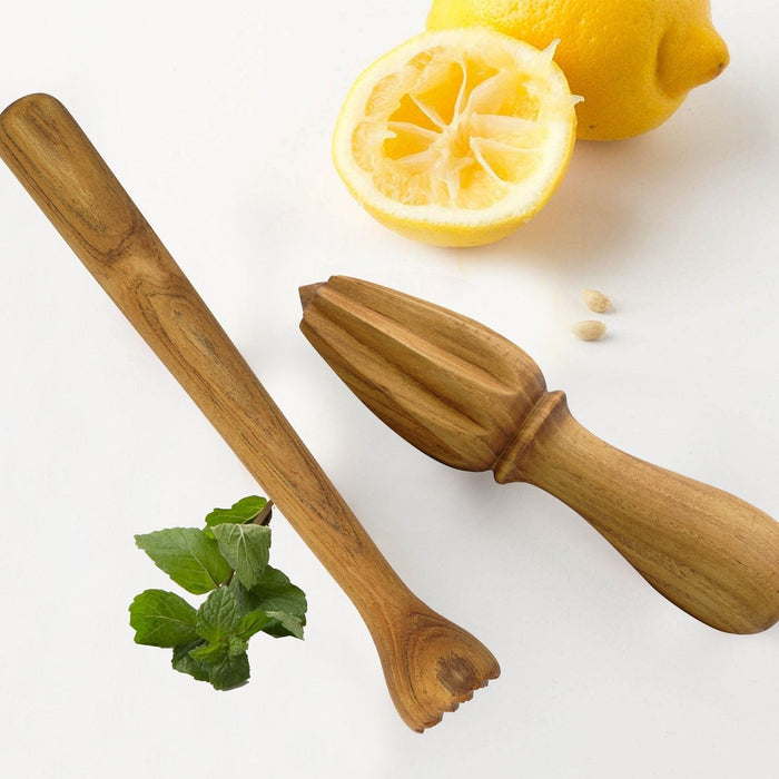 Teak citrus tamper and reamer with lemons and mint leaves on a white background