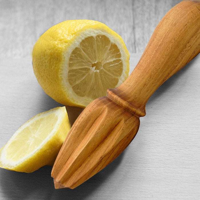 Teak cocktail reamer next to slices of lemons displayed on a light gray background