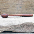 Wooden honey dipper displayed horizontally on a wooden background