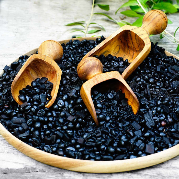 Set of 3 teak lentil scoop with short handles in a bowl of black lentils placed on a wooden surface