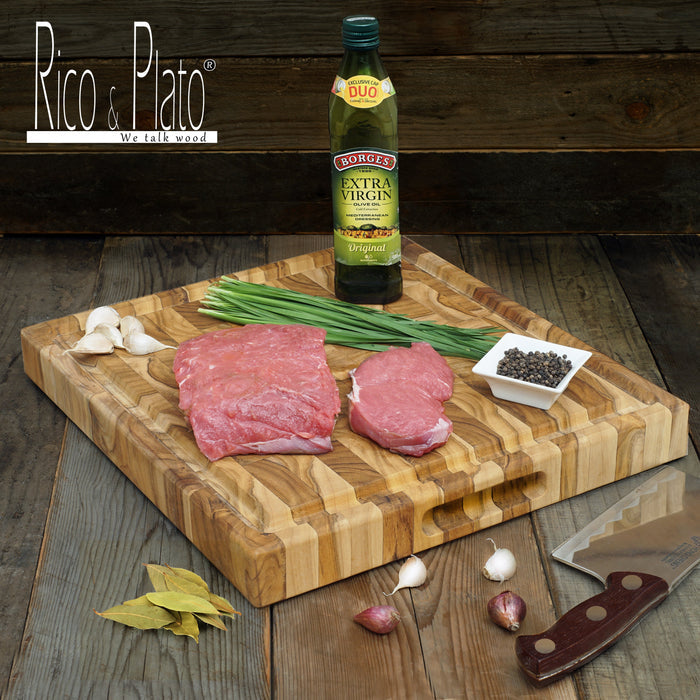 Meat, extra virgin olive oil, chives, peppercorn in a white dish, and garlic placed on an end grain cutting board with juice groove and handles with a cleaver next to it on a wooden background