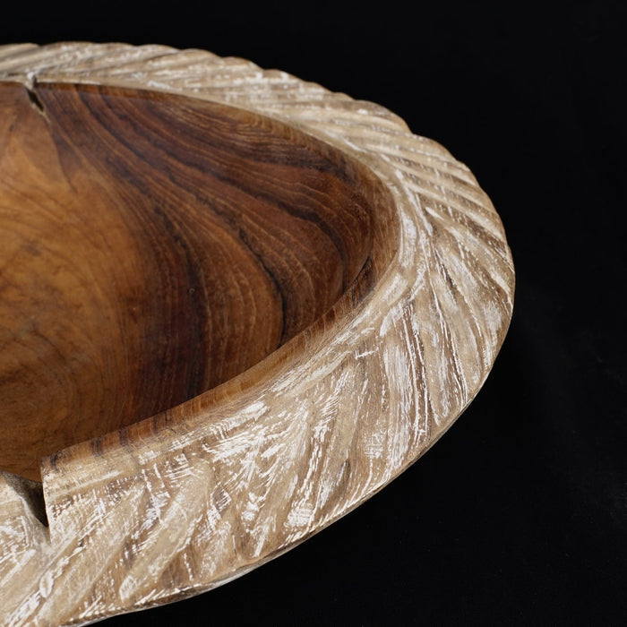 Close up of the whitewashed edge of a teak bowl displayed on a black background