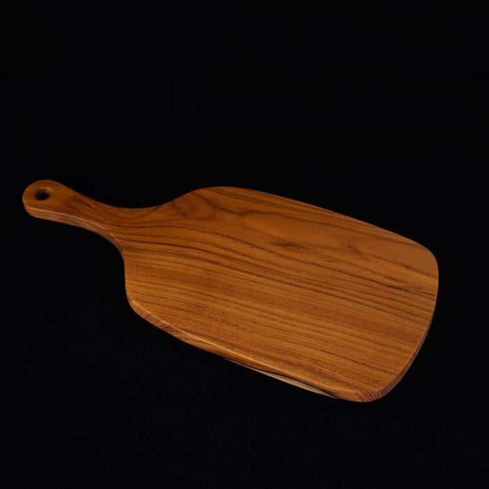 Teak cutting board/serving platter shaped as a paddle displayed on a black background
