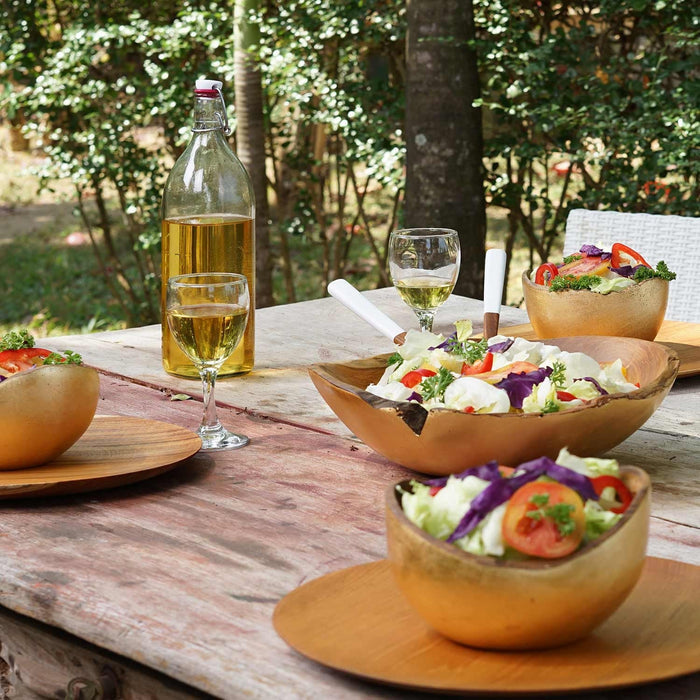 4 Rico & Plato teak salad bowls with salad inside each bowl outside on a wooden table
