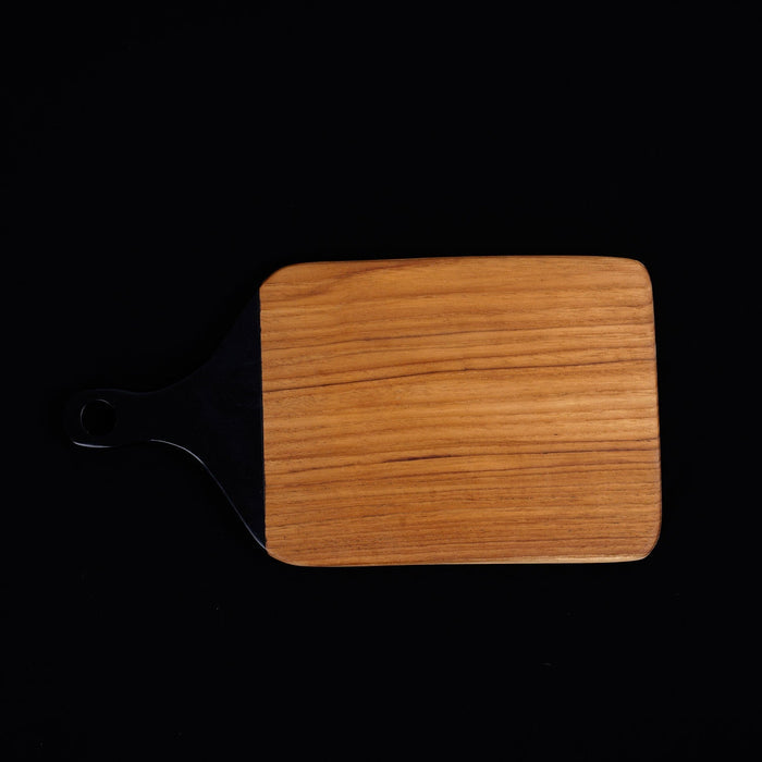 Top view of square shaped teak cutting board/serving platter with black handle displayed on a black background